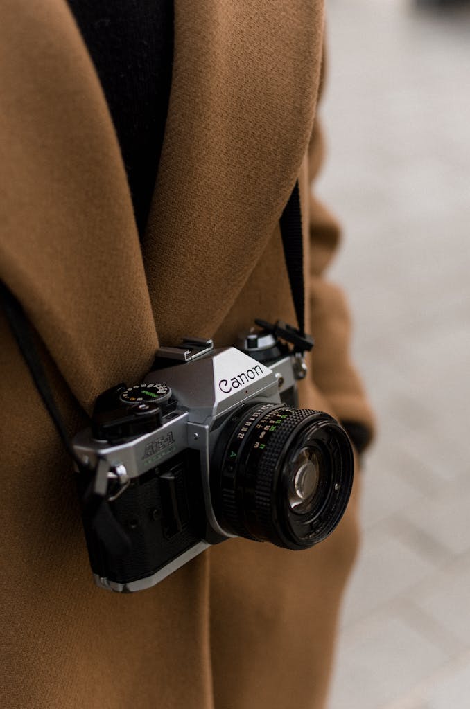 A vintage Canon film camera worn by a photographer outdoors, showcasing classic photography equipment.